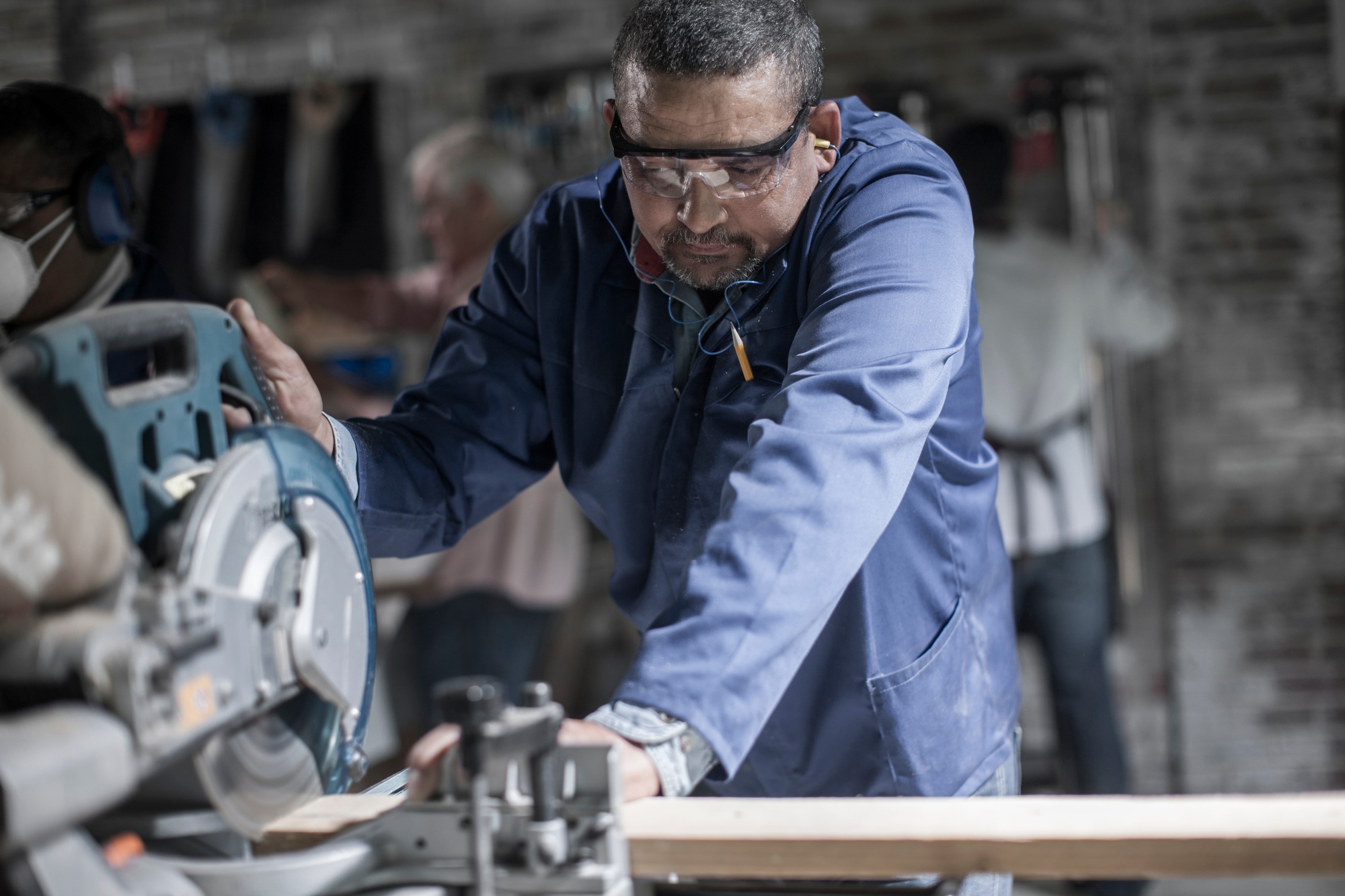 Carpenter sawing plank of wood in workshop